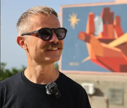 Basik standing in front of a mural