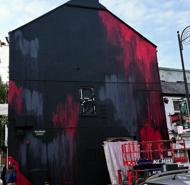 Dark base colours and pink brush marks being prepared on a gable wall in Dundalk