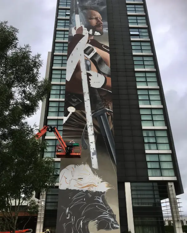 Lugh by Smug being painted high on the side of The Gateway Hotel