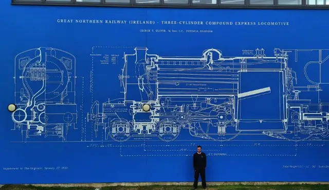 A person standing in front of Mack Signs’ blue Great Northern Railway blueprint mural